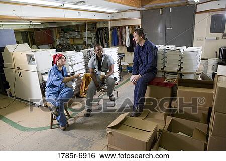View of two men and a woman enjoying a coffee break while working in a warehouse View Large Photo Image Stock Photograph - View of two men and a woman enjoying a coffee break while working in a warehouse. Fotosearch
