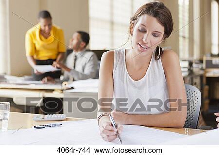 Woman at desk looking over plans View Large Photo Image Picture - Woman at desk looking over plans. Fotosearch