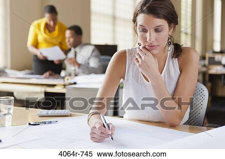 Woman at desk looking over plans View Large Photo Image Stock Photography - Woman at desk looking over plans. Fotosearch