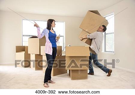 Stock Image - Woman drinking wine while telling her husband to move boxes. Fotosearch