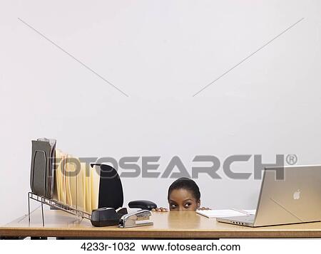 Woman hiding behind desk over colored background View Large Photo Image Stock Image - Woman hiding behind desk over colored background. Fotosearch