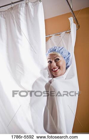 Stock Image - Woman in shower cap peeking out from behind curtain. Fotosearch