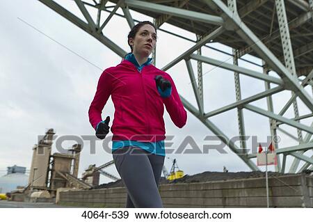 Stock Photo - Woman running underneath bridge. Fotosearch