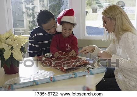 Woman, teenage son and young daughter wrapping gifts on kitchen table View Large Photo Image Stock Image - Woman, teenage son and young daughter wrapping gifts on kitchen table. Fotosearch