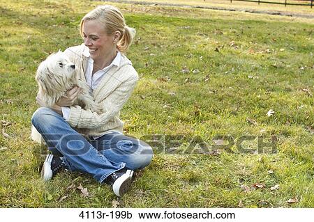Woman with white dog sitting on field View Large Photo Image Stock Image - Woman with white dog sitting on field. Fotosearch