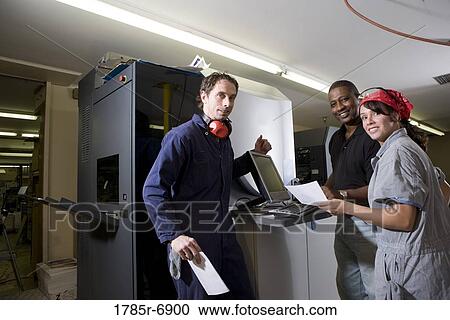 Stock Image - Workers being trained to use a piece of machinery with computer controls. Fotosearch