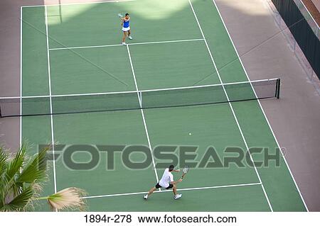 Stock Photo - Young couple playing tennis in the court of a tourist resort. Fotosearch