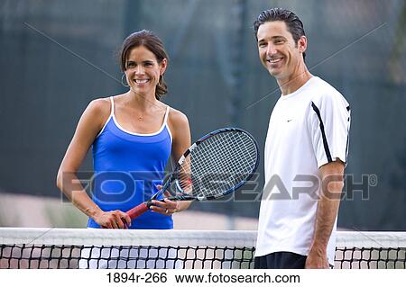 Stock Photograph - Young couple playing tennis in the court of a tourist resort. Fotosearch