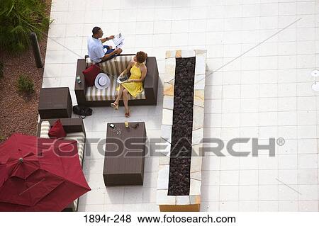 Stock Photo - Young couple reading newspapers in a tourist resort. Fotosearch