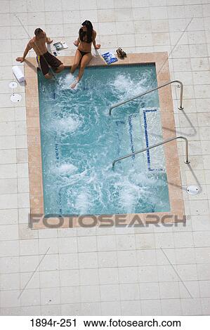 Young couple sitting at the poolside View Large Photo Image Stock Image - Young couple sitting at the poolside. Fotosearch