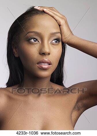 Stock Photograph - Young depressed woman holding head over colored background. Fotosearch
