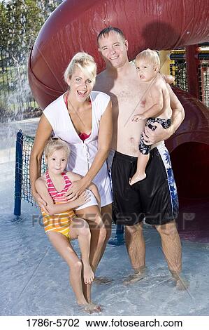 Stock Image - Young family playing at water park. Fotosearch