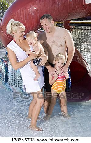 Stock Image - Young family playing at water park. Fotosearch