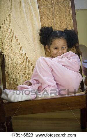 Young girl in pajamas sitting playfully on armchair View Large Photo Image Stock Image - Young girl in pajamas sitting playfully on armchair. Fotosearch
