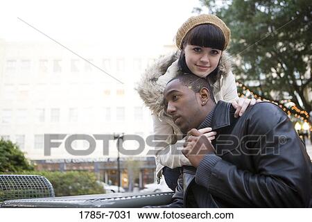 Young inter-racial couple embracing on a park bench View Large Photo Image Stock Image - Young inter-racial couple embracing on a park bench. Fotosearch