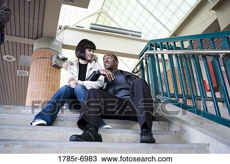 Young inter-racial couple sitting at the top of a flight of stairs View Large Photo Image Stock Image - Young inter-racial couple sitting at the top of a flight of stairs. Fotosearch