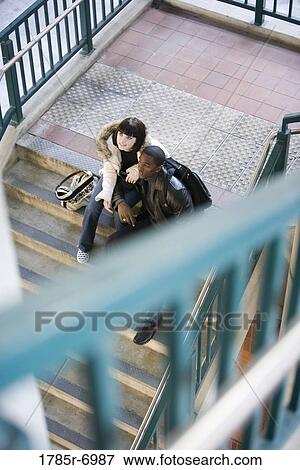 Young inter-racial couple sitting at the bottom of a flight of stairs at a public train station View Large Photo Image Stock Photo - Young inter-racial couple sitting at the bottom of a flight of stairs at a public train station. Fotosearch
