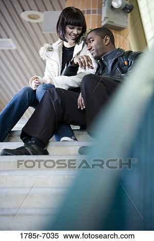 Young inter-racial couple sitting at the top of a flight of stairs at a public train station View Large Photo Image Stock Photography - Young inter-racial couple sitting at the top of a flight of stairs at a public train station. Fotosearch