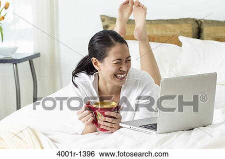 Young woman looking at a laptop and smiling View Large Photo Image Stock Photograph - Young woman looking at a laptop and smiling. Fotosearch