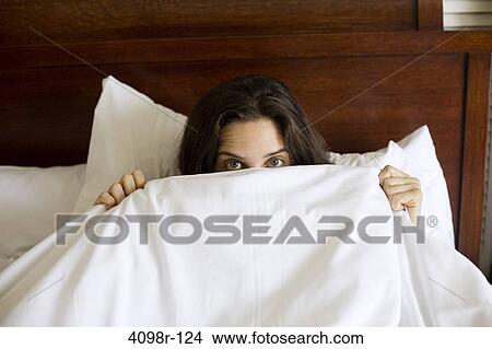 Young woman peeking from a bed sheet View Large Photo Image Picture - Young woman peeking from a bed sheet. Fotosearch