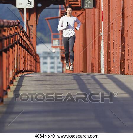 Young woman running along bridge View Large Photo Image Stock Image - Young woman running along bridge. Fotosearch