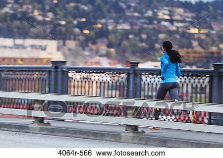 Young woman running along bridge View Large Photo Image Stock Photograph - Young woman running along bridge. Fotosearch