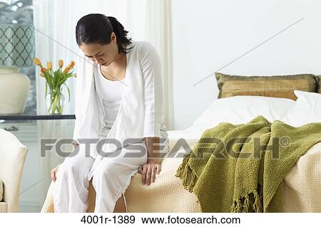 Young woman sitting on the bed in her bedroom View Large Photo Image Stock Photo - Young woman sitting on the bed in her bedroom. Fotosearch