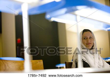 Young woman wearing a head scarf sitting in the reading room of a library View Large Photo Image Stock Image - Young woman wearing a head scarf sitting in the reading room of a library. Fotosearch