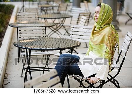 Young woman wearing a head scarf sitting at a table View Large Photo Image Stock Photo - Young woman wearing a head scarf sitting at a table. Fotosearch