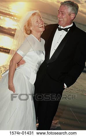 Stock Image - Bride and bridegroom standing at the beach. Fotosearch
