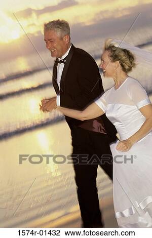 Stock Image - Bride and bridegroom walking on the beach. Fotosearch