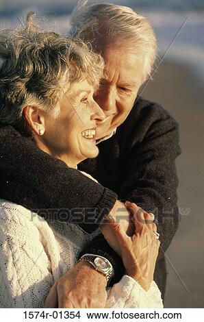 Picture - Close-up of a senior couple holding each other at the beach. Fotosearch