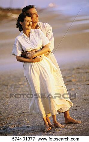Stock Photo - Couple holding each other standing on the beach. Fotosearch
