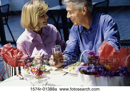 Couple sitting at a table outdoors View Large Photo Image Stock Image - Couple sitting at a table outdoors. Fotosearch