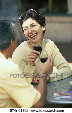 Stock Image - Couple sitting together toasting with red wine. Fotosearch