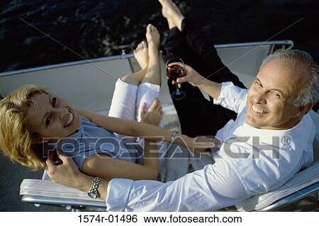 Stock Photograph - High angle view of a couple relaxing on a yacht. Fotosearch