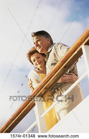 Stock Photo - Low angle view of a couple standing against the railing of a ship. Fotosearch