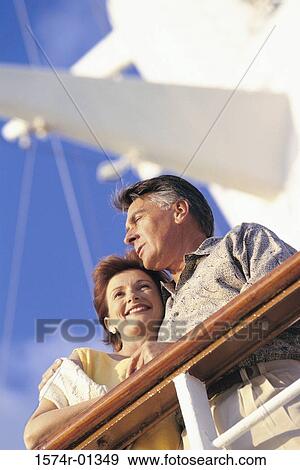 Stock Photo - Low angle view of a couple standing against the railing of a ship. Fotosearch