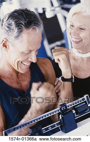Stock Image - Man standing on a weighing scale. Fotosearch