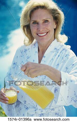 Mid adult woman pouring a glass of orange juice View Large Photo Image Stock Image - Mid adult woman pouring a glass of orange juice. Fotosearch