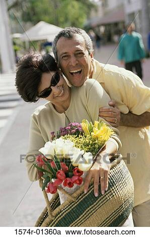 Portrait of a couple smiling holding a bouquet of flowers View Large Photo Image Stock Image - Portrait of a couple smiling holding a bouquet of flowers. Fotosearch
