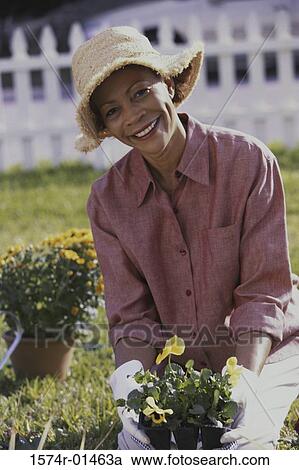 Stock Image - Portrait of a senior woman holding potted plants. Fotosearch