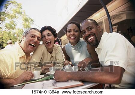 Stock Image - Portrait of two couples sitting at a table outdoors. Fotosearch
