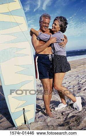 Senior couple at the beach near a surfboard View Large Photo Image Stock Photograph - Senior couple at the beach near a surfboard. Fotosearch