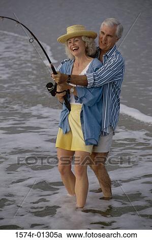 Stock Image - Senior couple fishing together on the beach. Fotosearch