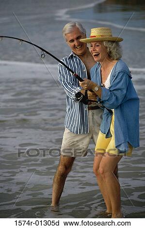 Stock Image - Senior couple fishing together on the beach. Fotosearch