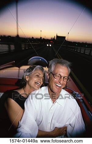 Stock Image - Senior couple laughing in a convertible car. Fotosearch