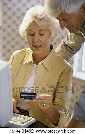 Stock Image - Senior couple looking at a credit card. Fotosearch