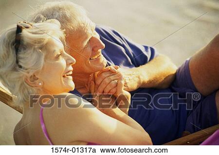 Stock Image - Senior couple lying on the beach. Fotosearch