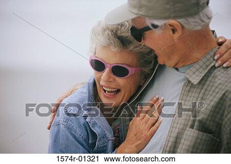 Stock Image - Senior couple standing together laughing. Fotosearch